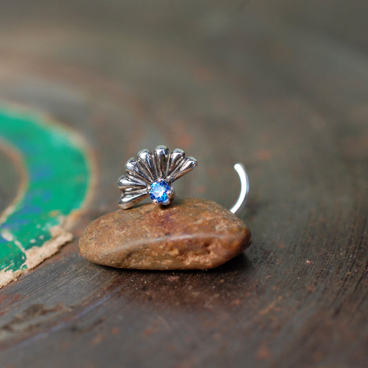 sapphire nose stud with a big silver fan behind it