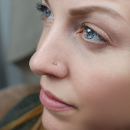 model wearing gold bar nose stud made of four dots