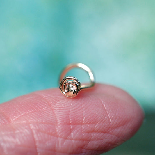 gold nose stud perched on a finger to show small size