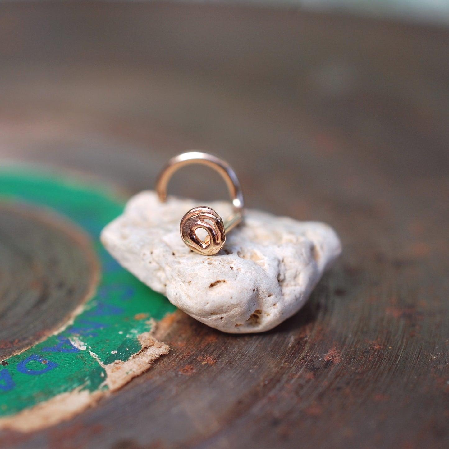 tiny gold nose stud made in a circular free-formed artistic scribble pattern