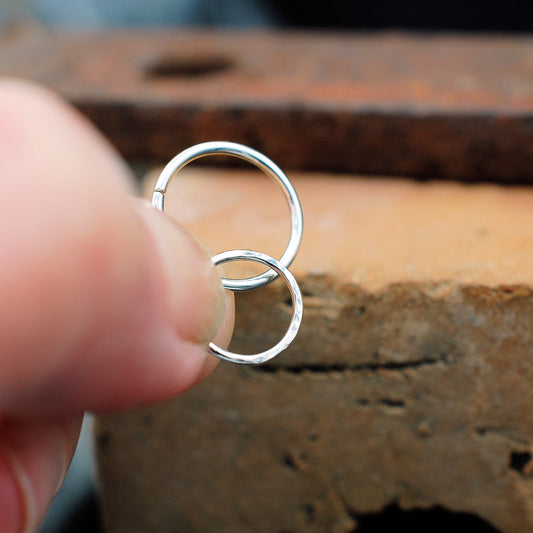 holding a pair of silver nose rings