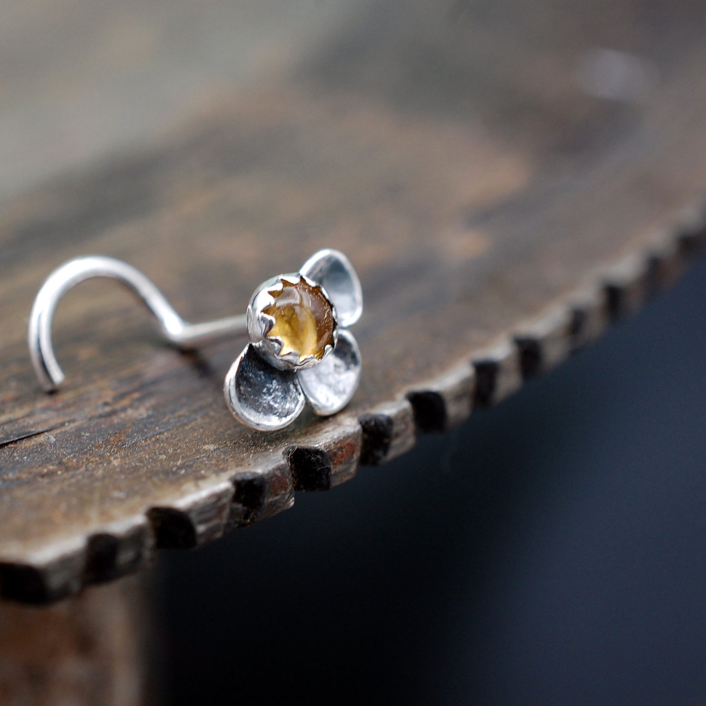 Silver nose stud with a yellow gemstone in a flower