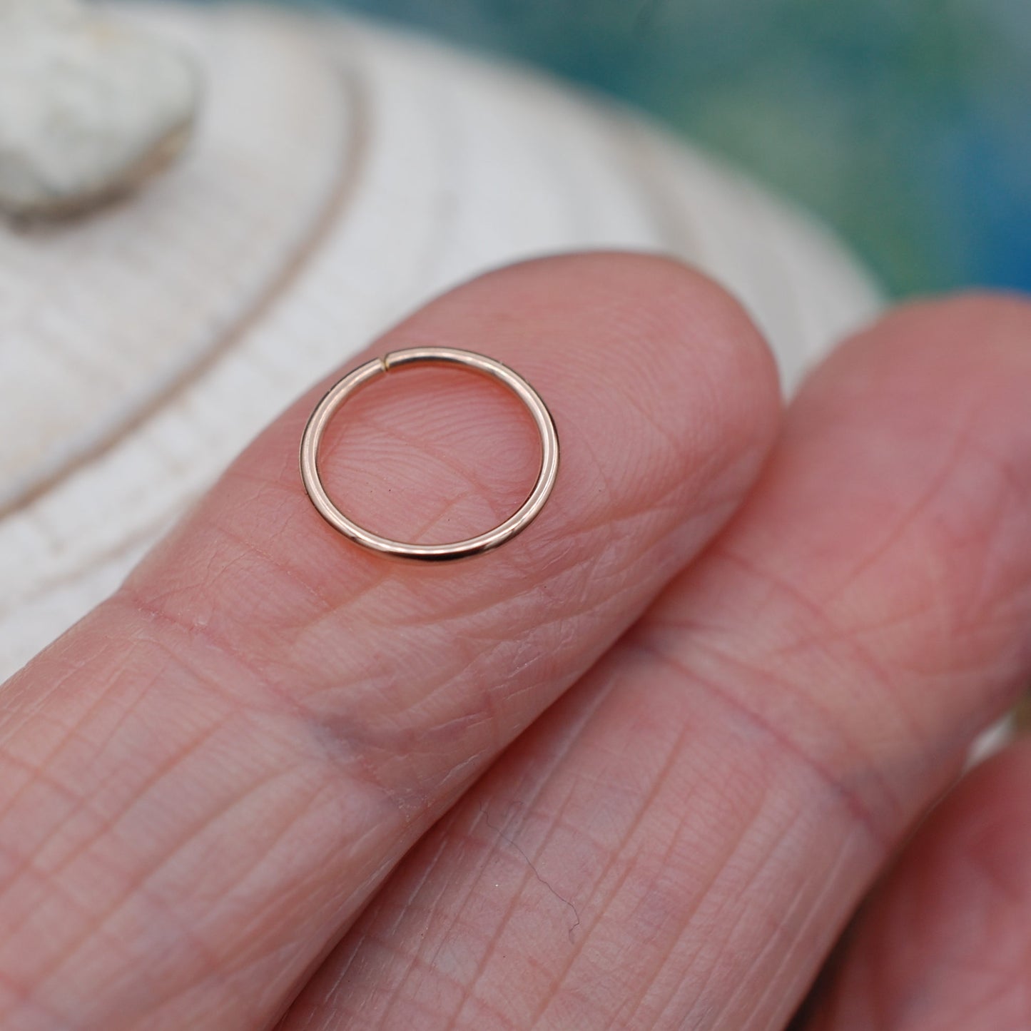 rose gold nose ring shown on an index finger