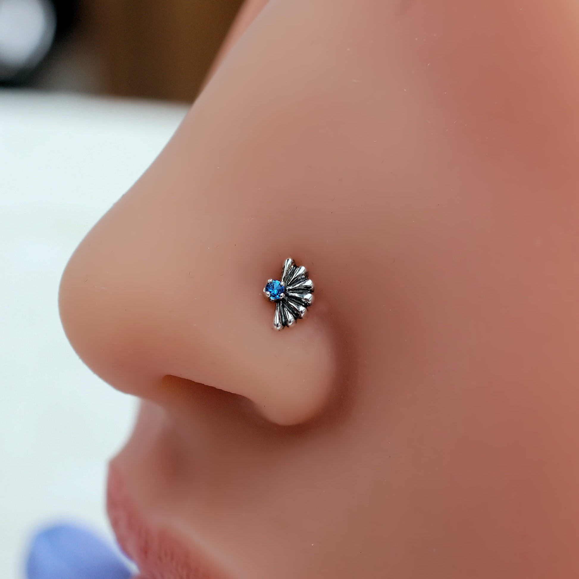 silver fan nose stud with little blue gemstone
