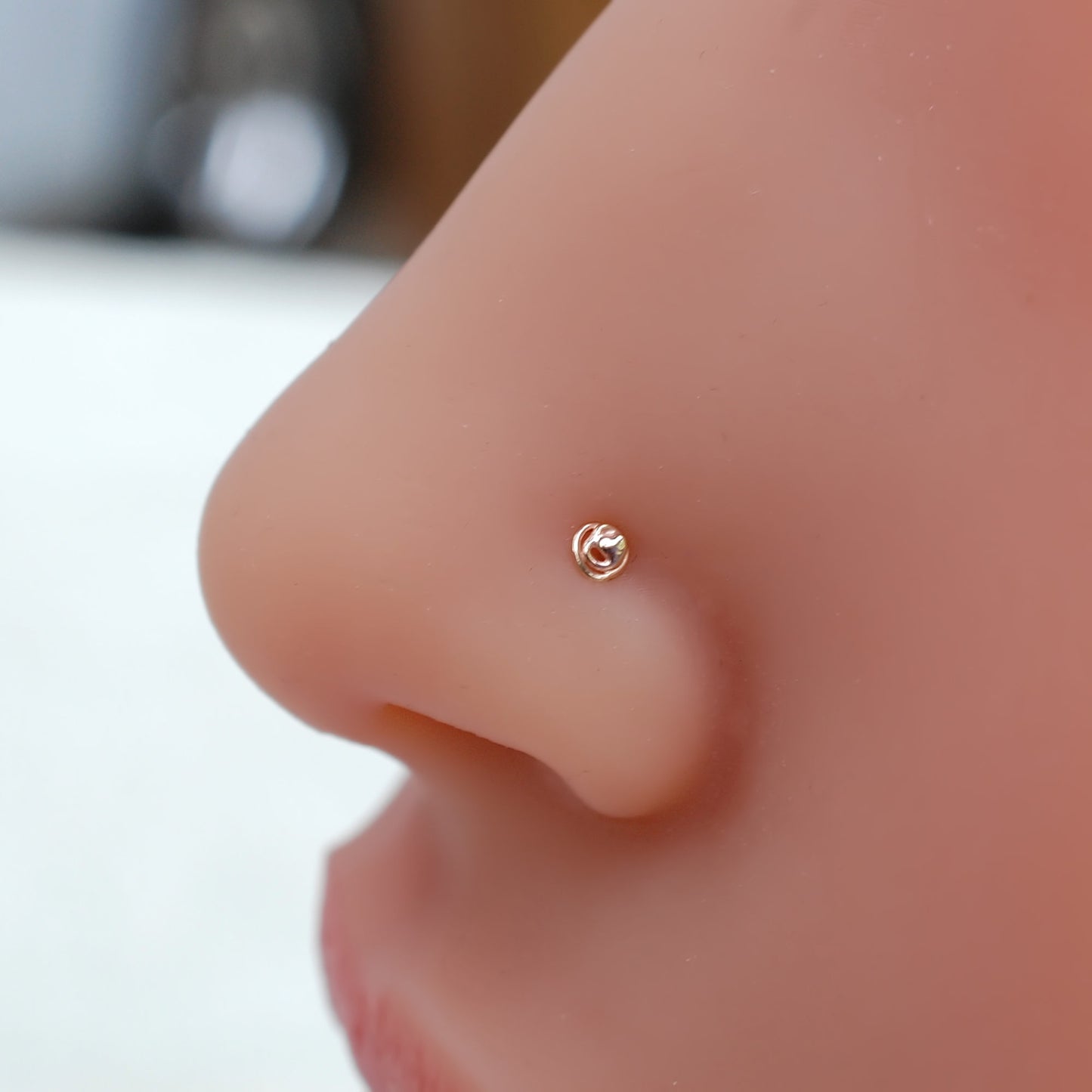 gold scribble nose stud on a nose