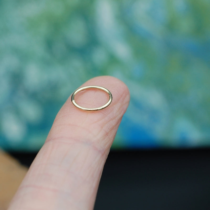 gold nose ring hoop shown on an index finger