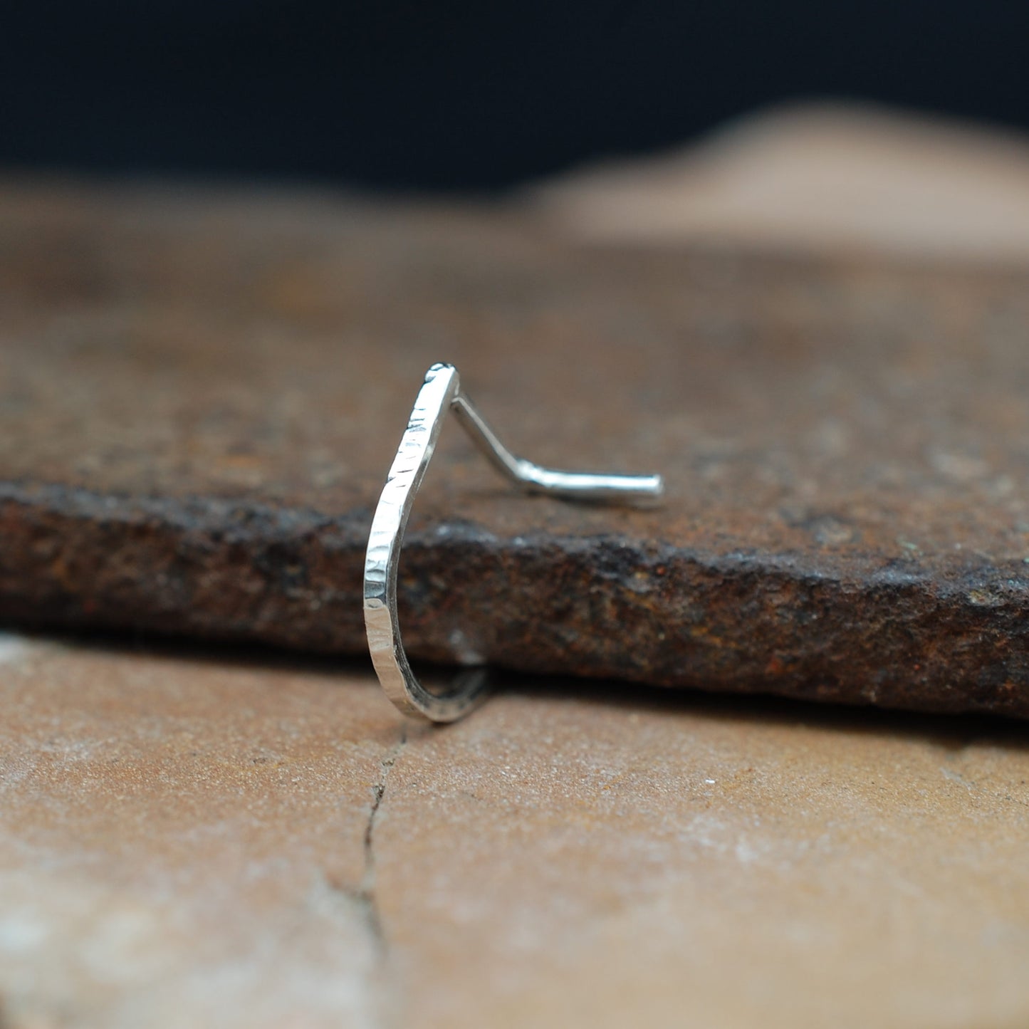 Silver nose ring on a textured stone surface