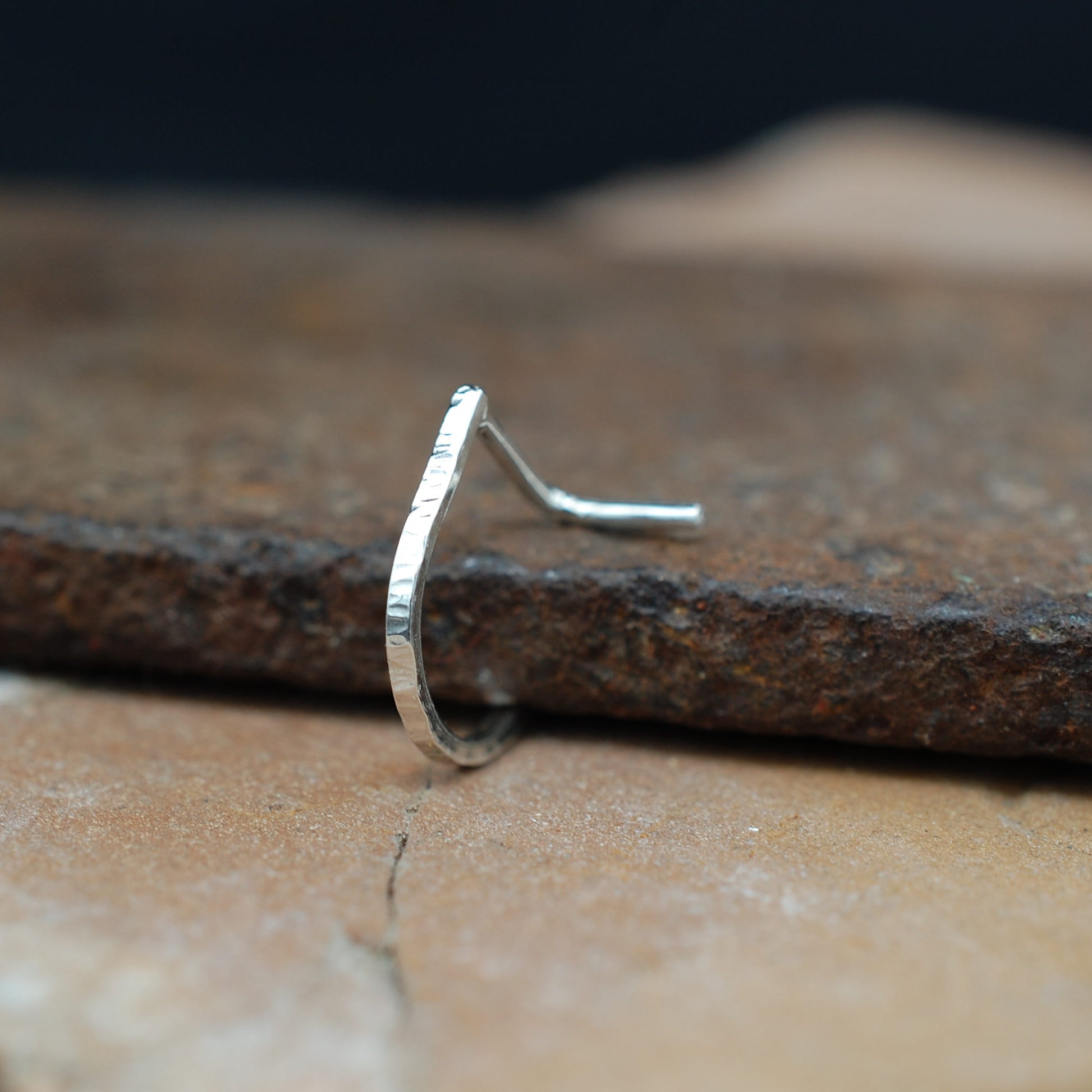 Silver nose ring on a textured stone surface