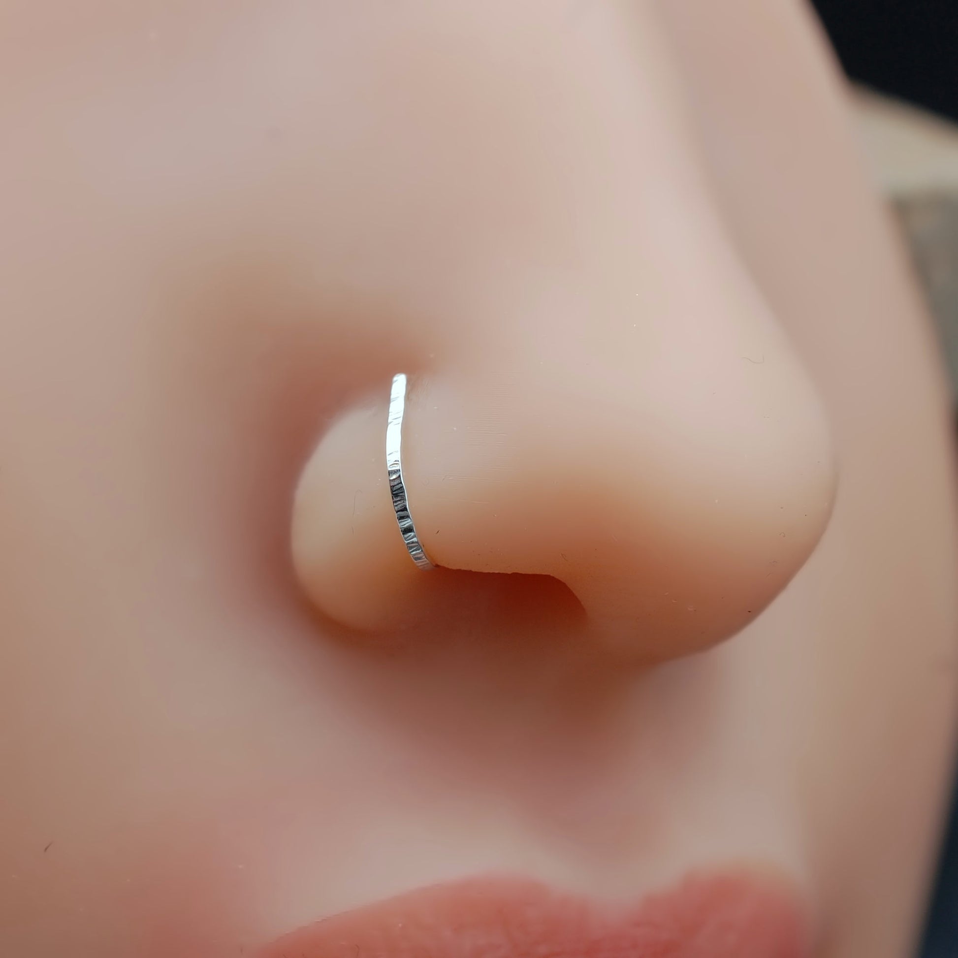 Close-up of a person wearing a silver nose ring.