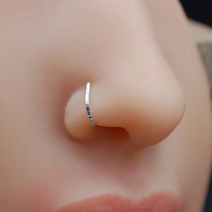 Close-up of a person wearing a silver nose ring.