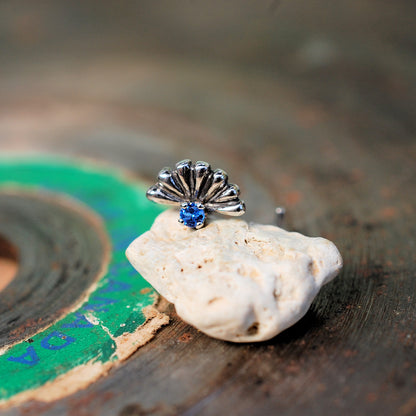 sapphire nose stud peeking over a rock and set with a blue gemstone
