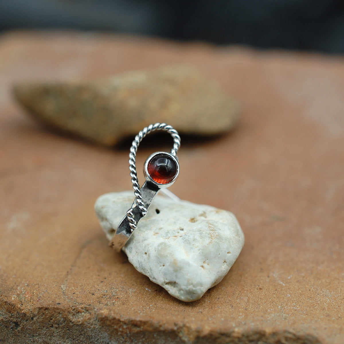 A hammered sterling silver garnet nose cuff with an open heart design staged on a stone surface.
