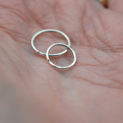 two silver nose rings held in a hand
