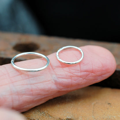 hammered and sleek silver nose rings on a finger