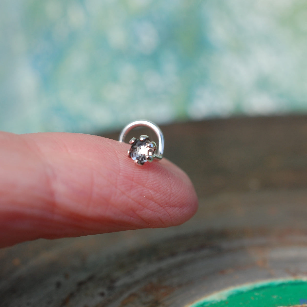 faceted white topaz nose stud on a finger set in sterling silver