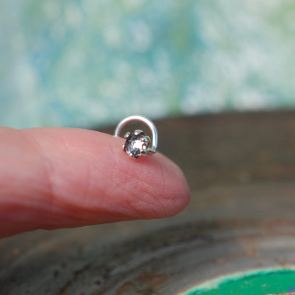 faceted white topaz nose stud on a finger set in sterling silver