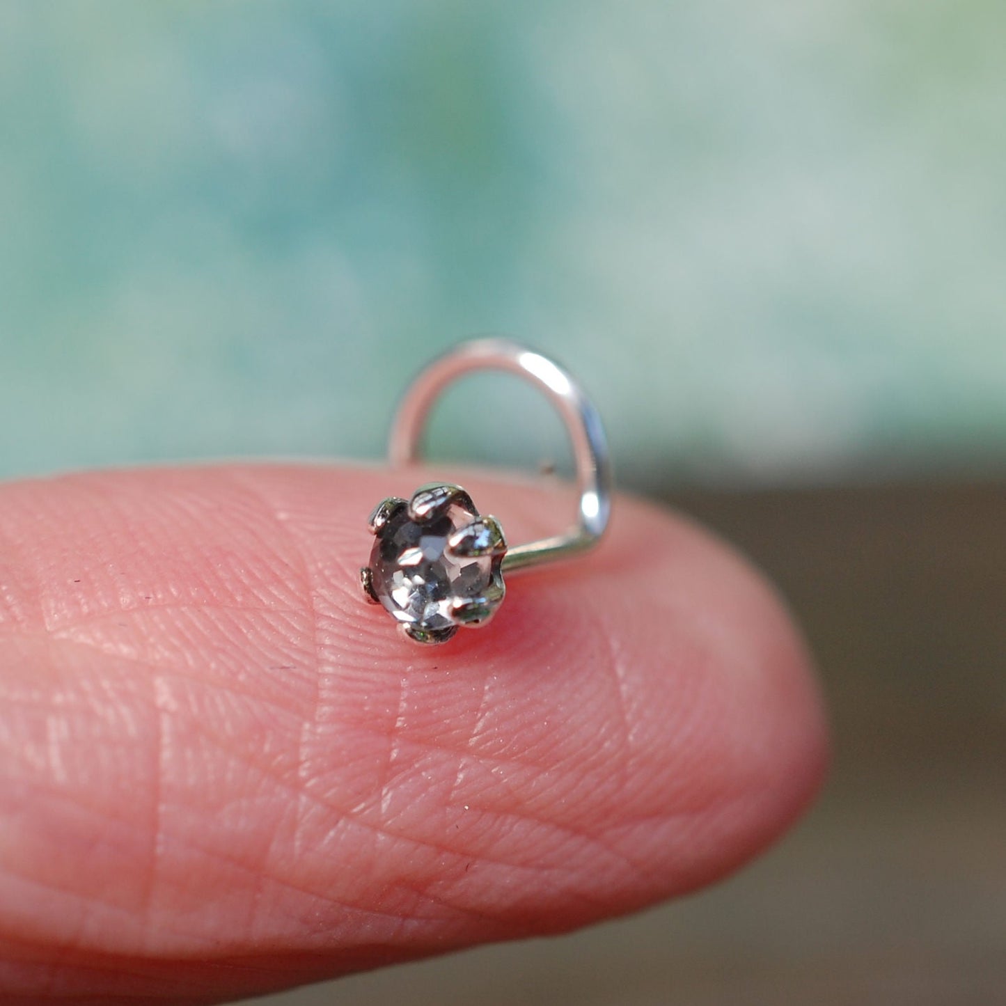 rose cut white topaz nose stud on a finger 