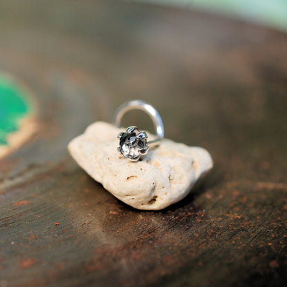 silver nose stud with white topaz sitting on a small rock