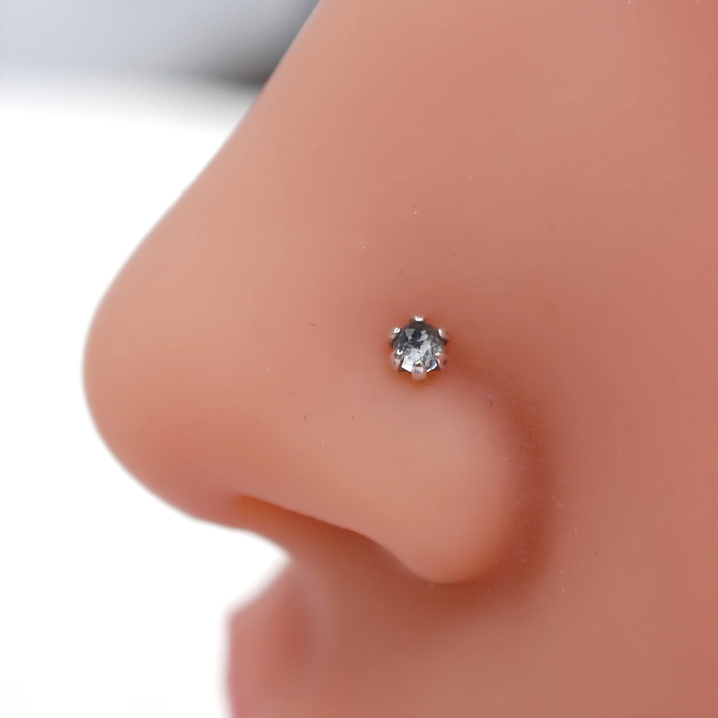faceted white topaz nose stud set in a silver claw setting
