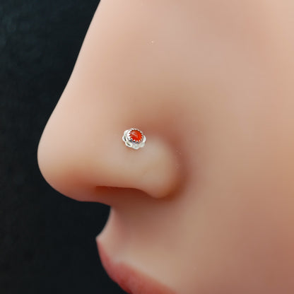 Nose stud on a nose showing silver flower with orange stone