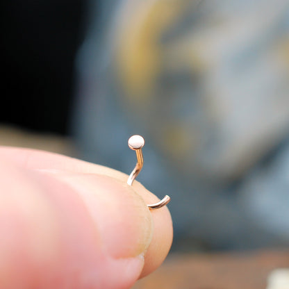 Rose gold nose ring on a finger with a blurred background