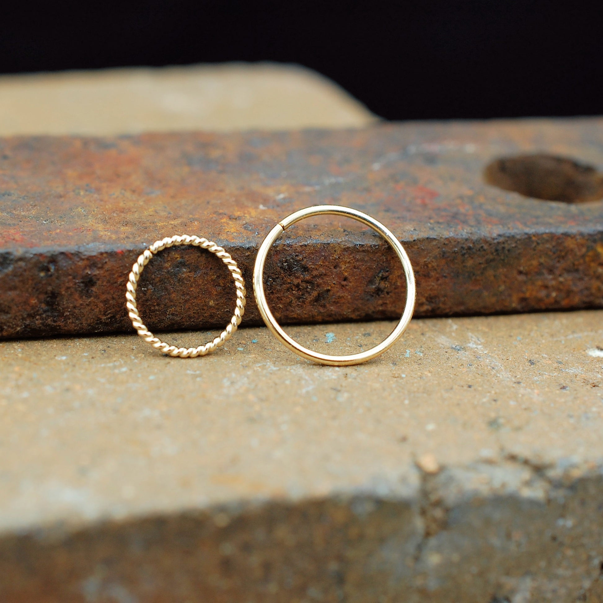 pair of nose rings one is twisted and one is sleek in gold
