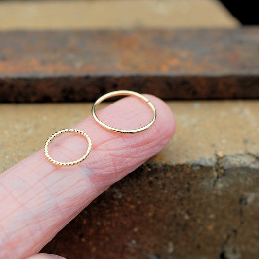 pair of nose rings in gold shown on a finger