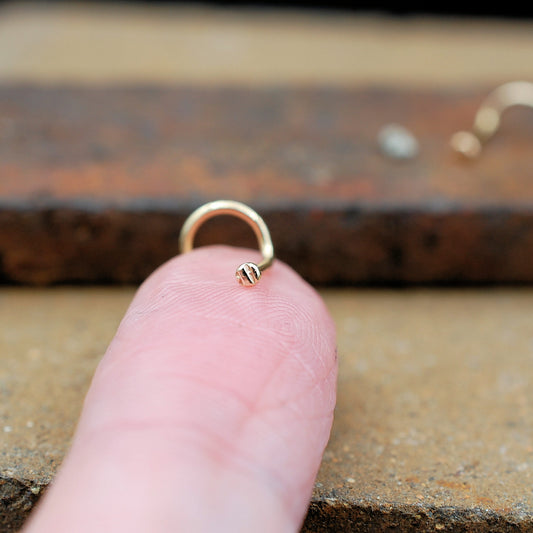 Gold stud textured on a finger against a rusty metal background