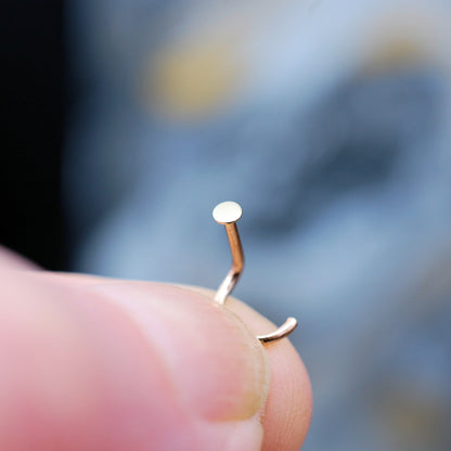 Gold nose ring on a finger with a blurred background