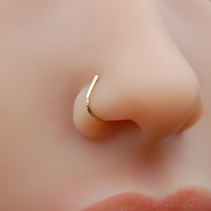 Close-up of a gold nose ring on a person's nose.