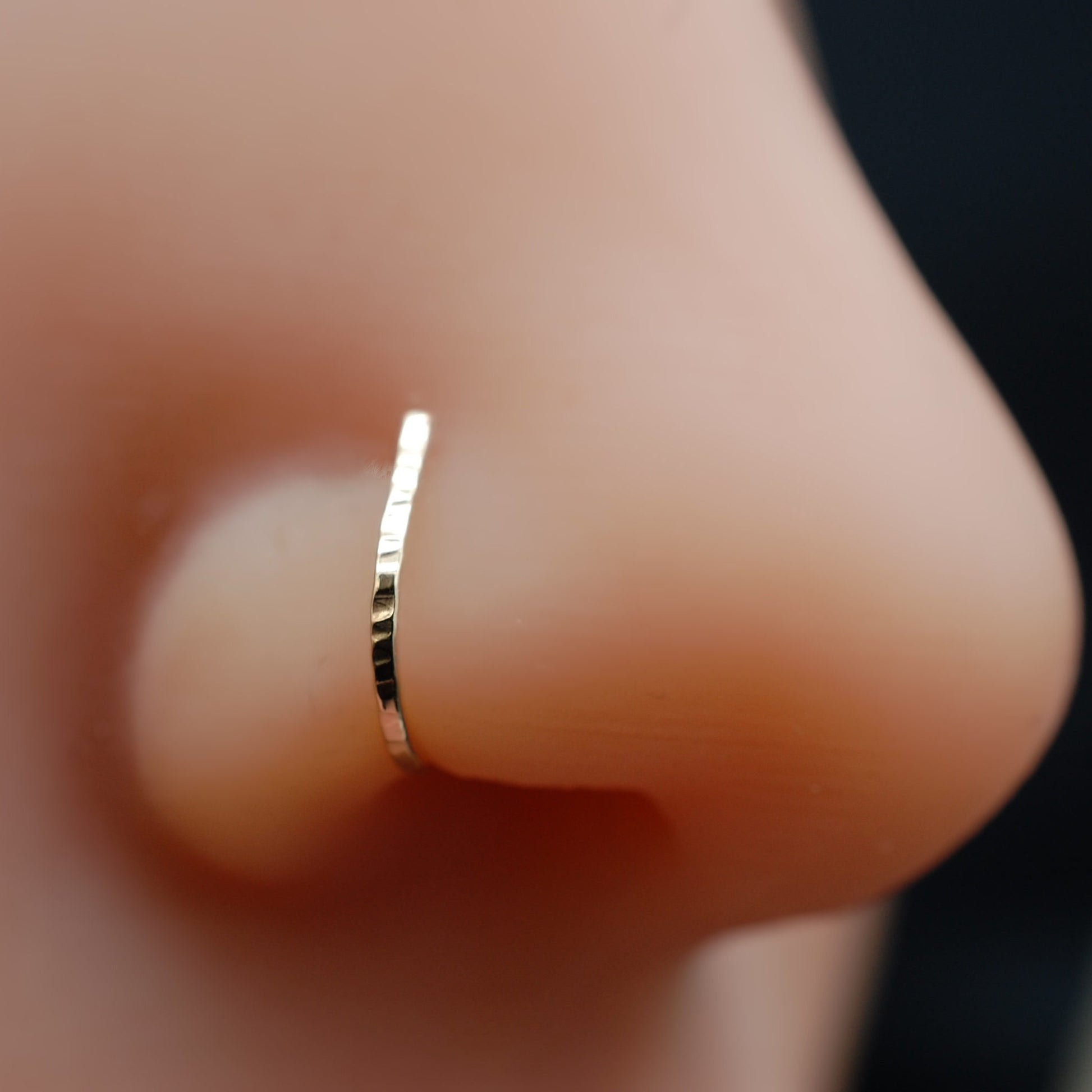 Gold nose ring on a person's nose with a blurred background